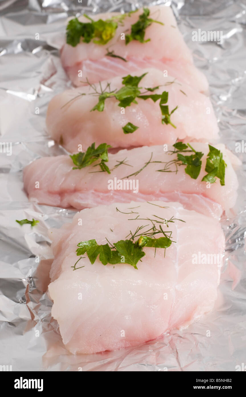 sliced monk fish and herbs laying on a sheet of tin foil Stock Photo