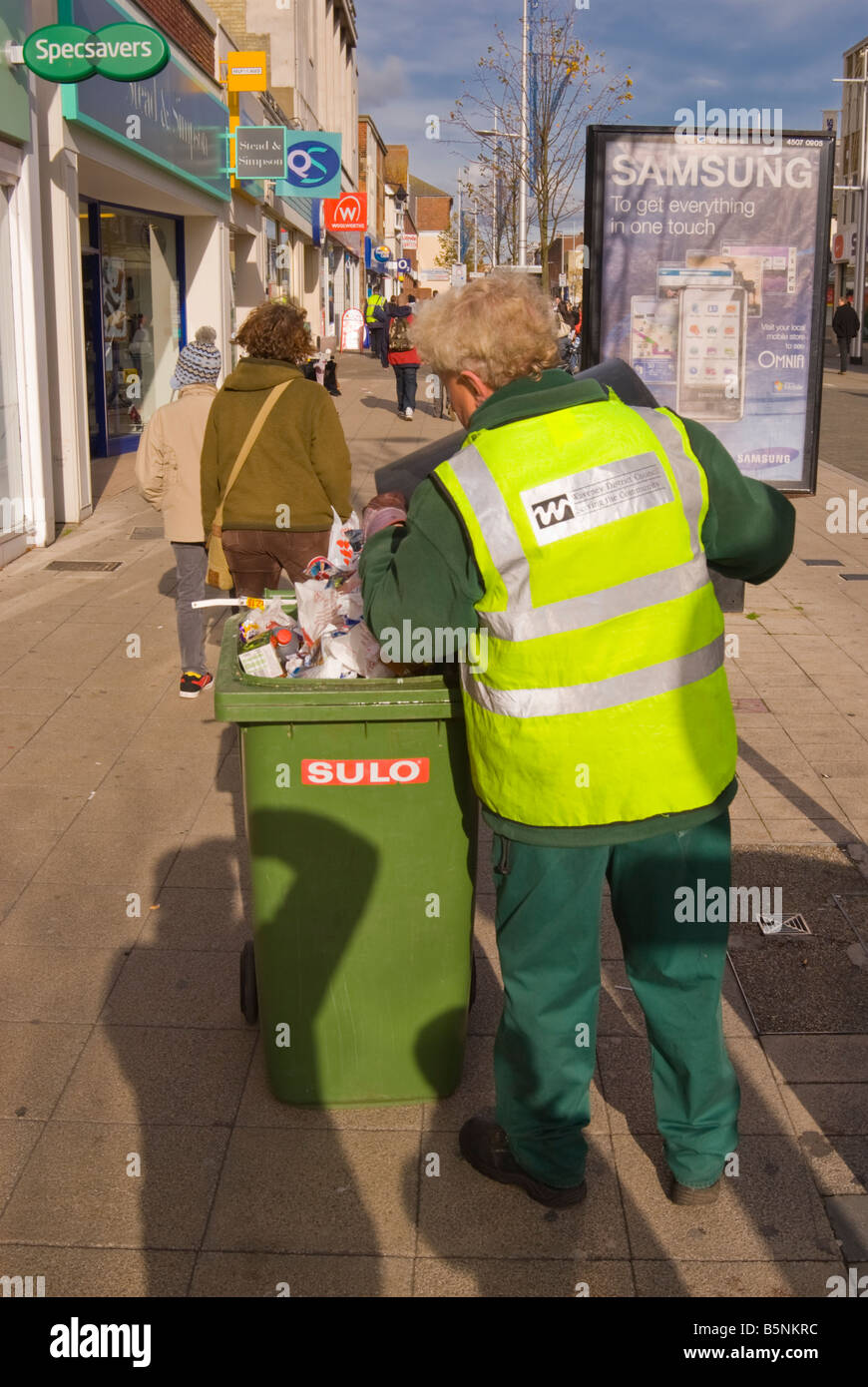 Waveney District Council worker clearing up litter and filling wheelie bin in the streets of Lowestoft,Suffolk,Uk Stock Photo
