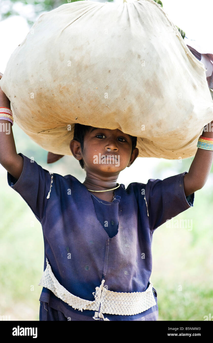 Poor young indian girl carrying clothes washing in a bundle on her