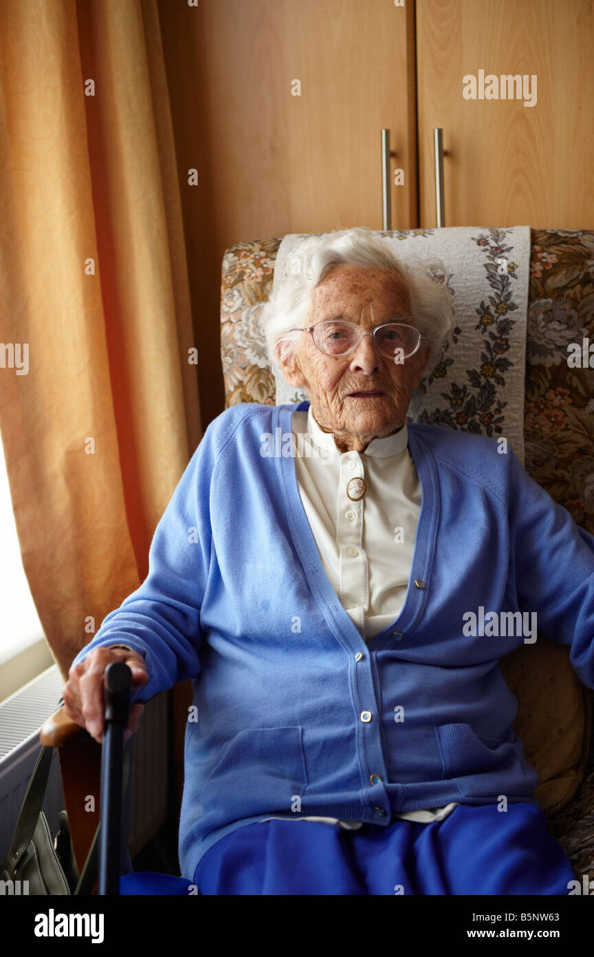 Elderly lady sitting in chair by window in old peoples home Stock Photo