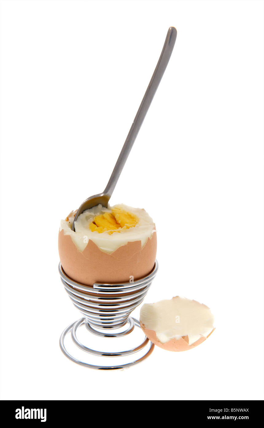 Boiled egg sitting in egg cup with top cut off and spoon sticking out Stock Photo