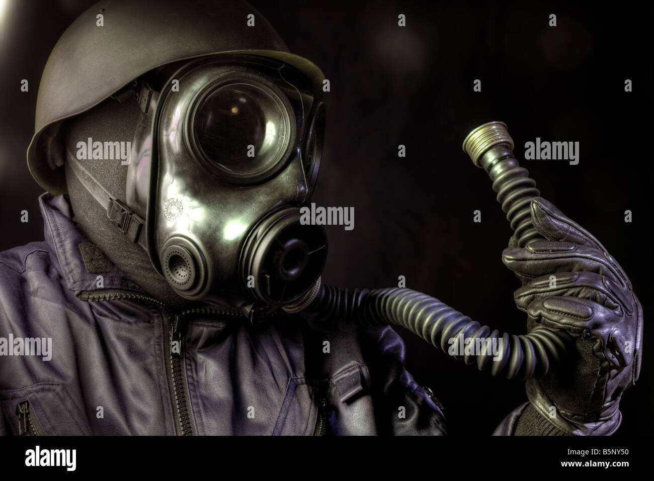Gas masked man looking at his breathing tube Stock Photo
