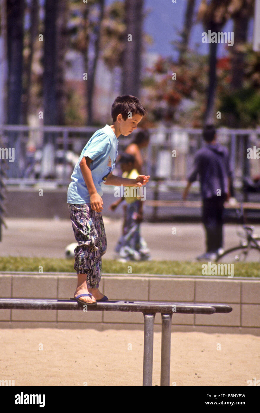 Boy balances on metal parallel bars in public park Stock Photo