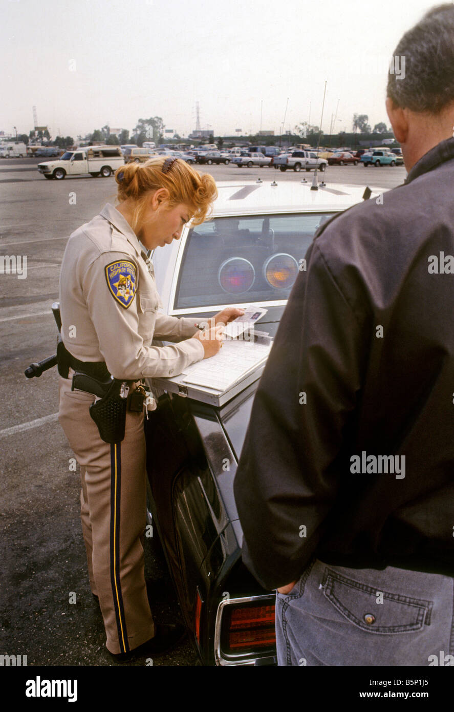 Female California Highway Patrol officer writes citation to driver. Stock Photo
