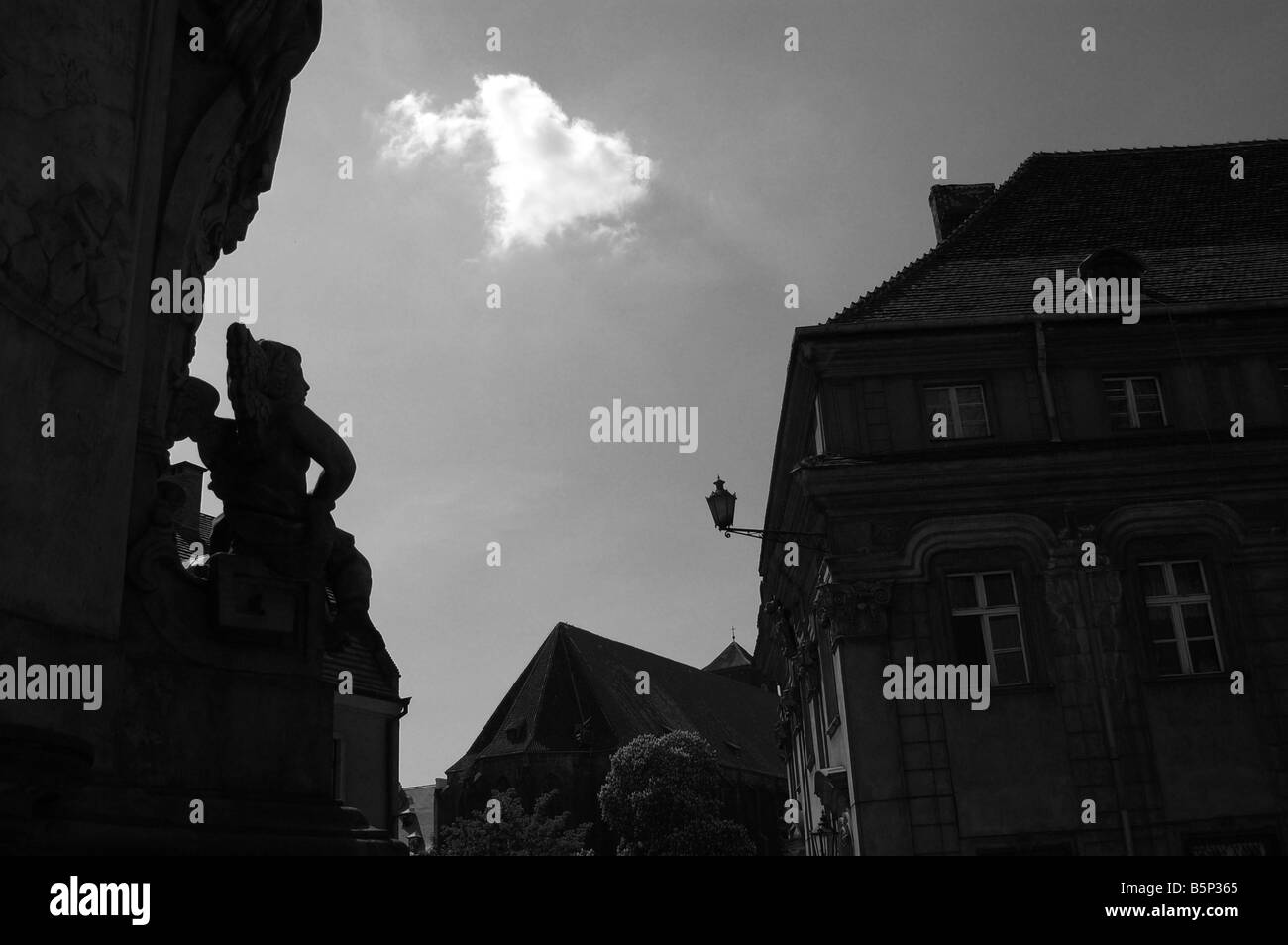 Cloud shaped as a heart with an arrow through it. Foreground statue of cupid. Stock Photo