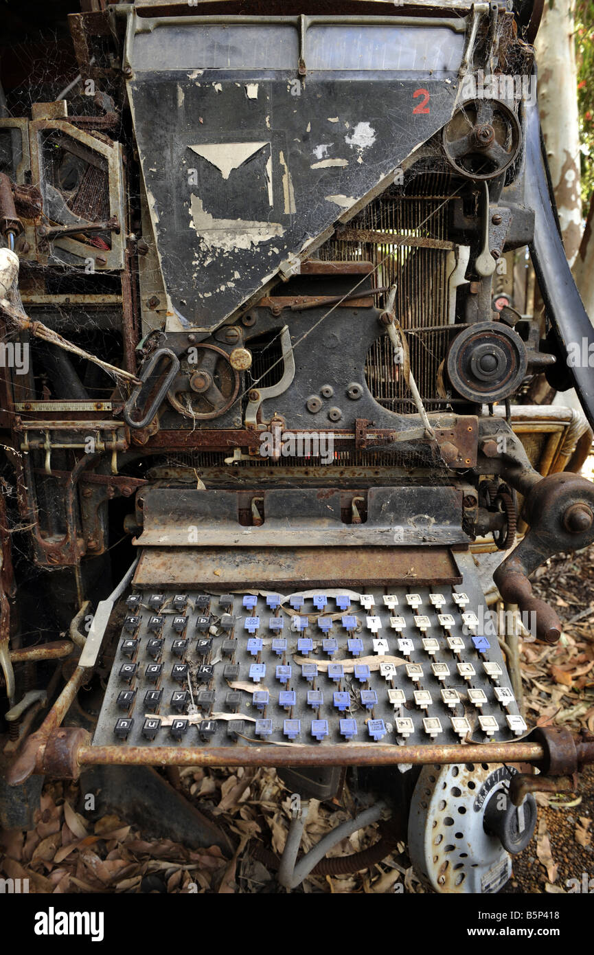 An old Linotype machine used in printing sits rusting in a vacant lot. Stock Photo