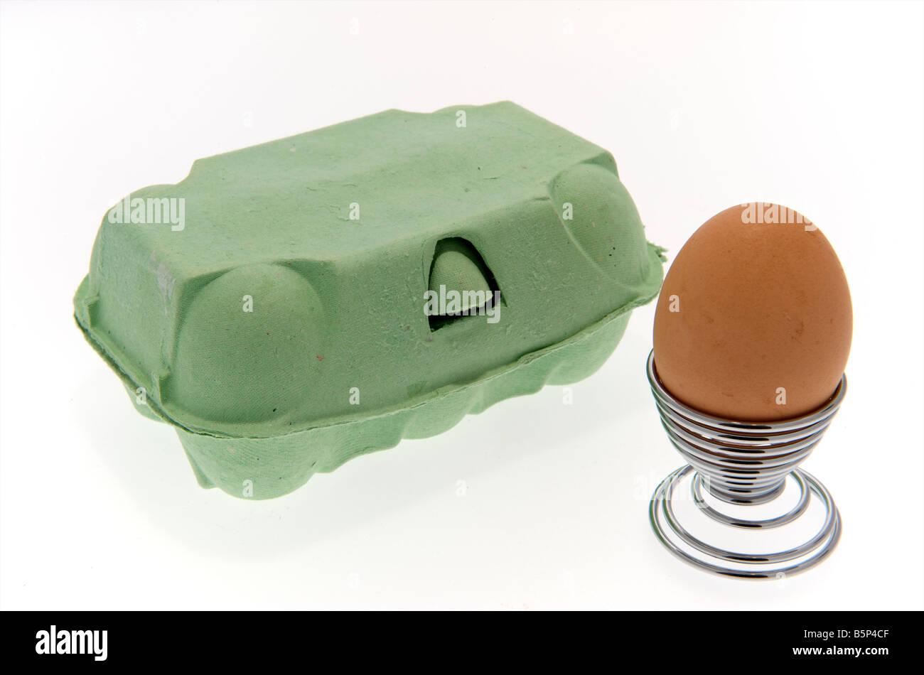 Egg in egg cup beside a box of eggs on white background Stock Photo