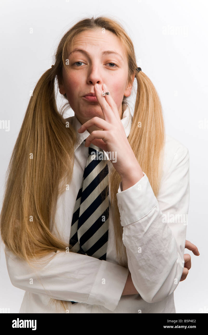 A Teenage schoolgirl wearing school uniform and tie smoking cigarette with her blonde hair in bunches, UK Stock Photo