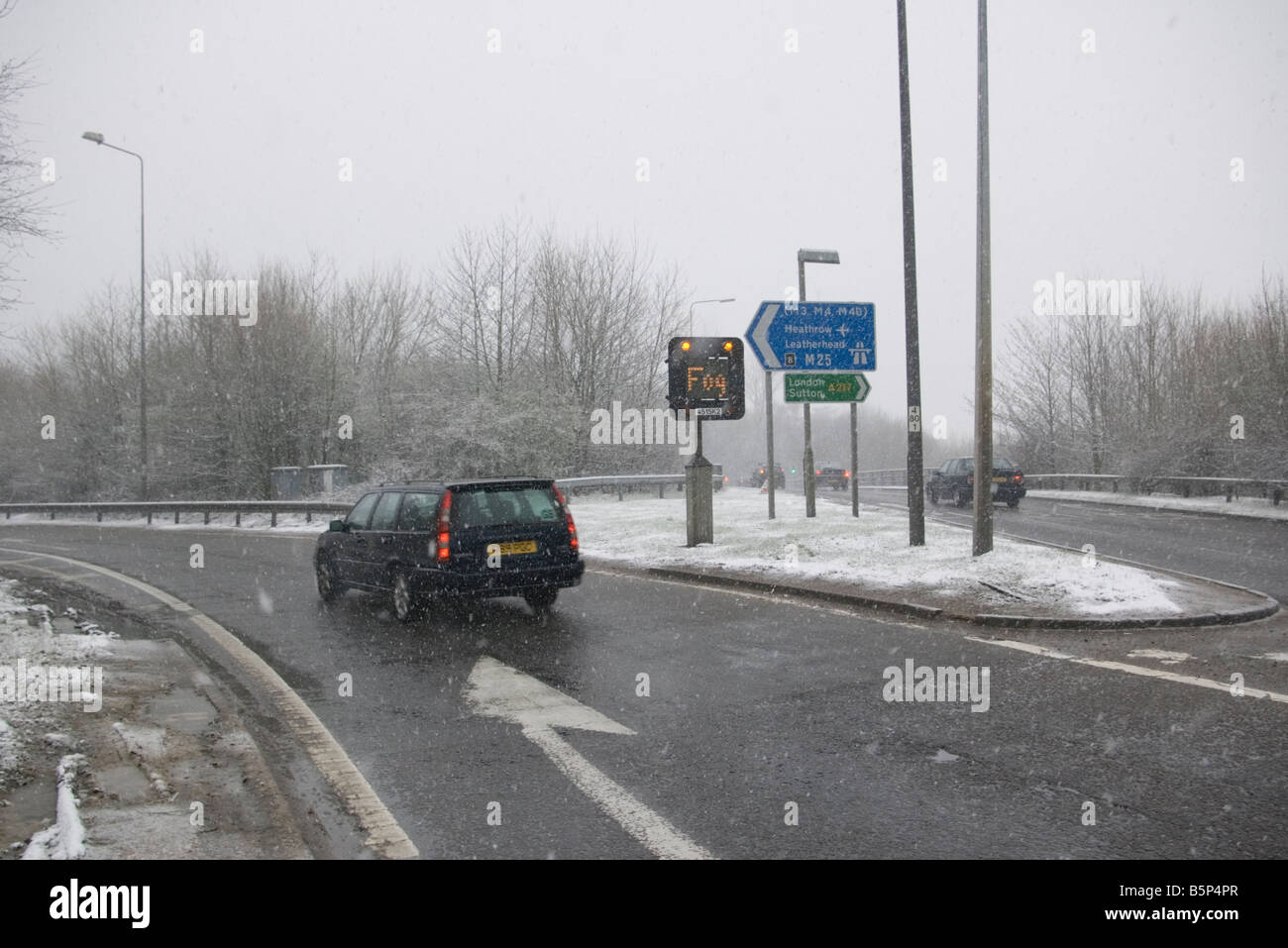 Car Driving In Sleet and Snow Bad Driving Conditions With A Fog Sign Displayed Stock Photo
