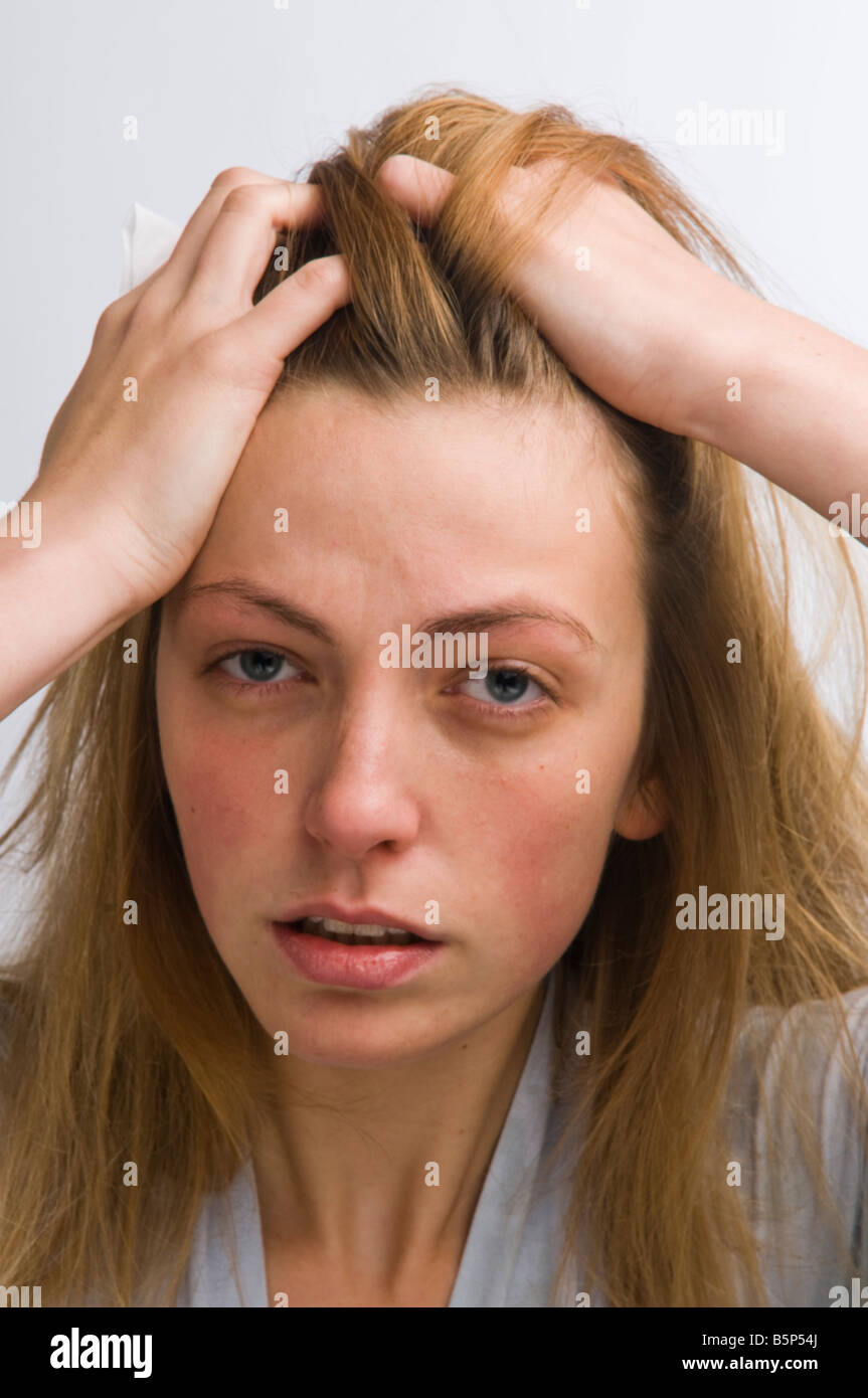 young woman looking hungover, feeling ill or sick, bleary eyed, pulling her blonde hair back off her face, UK Stock Photo