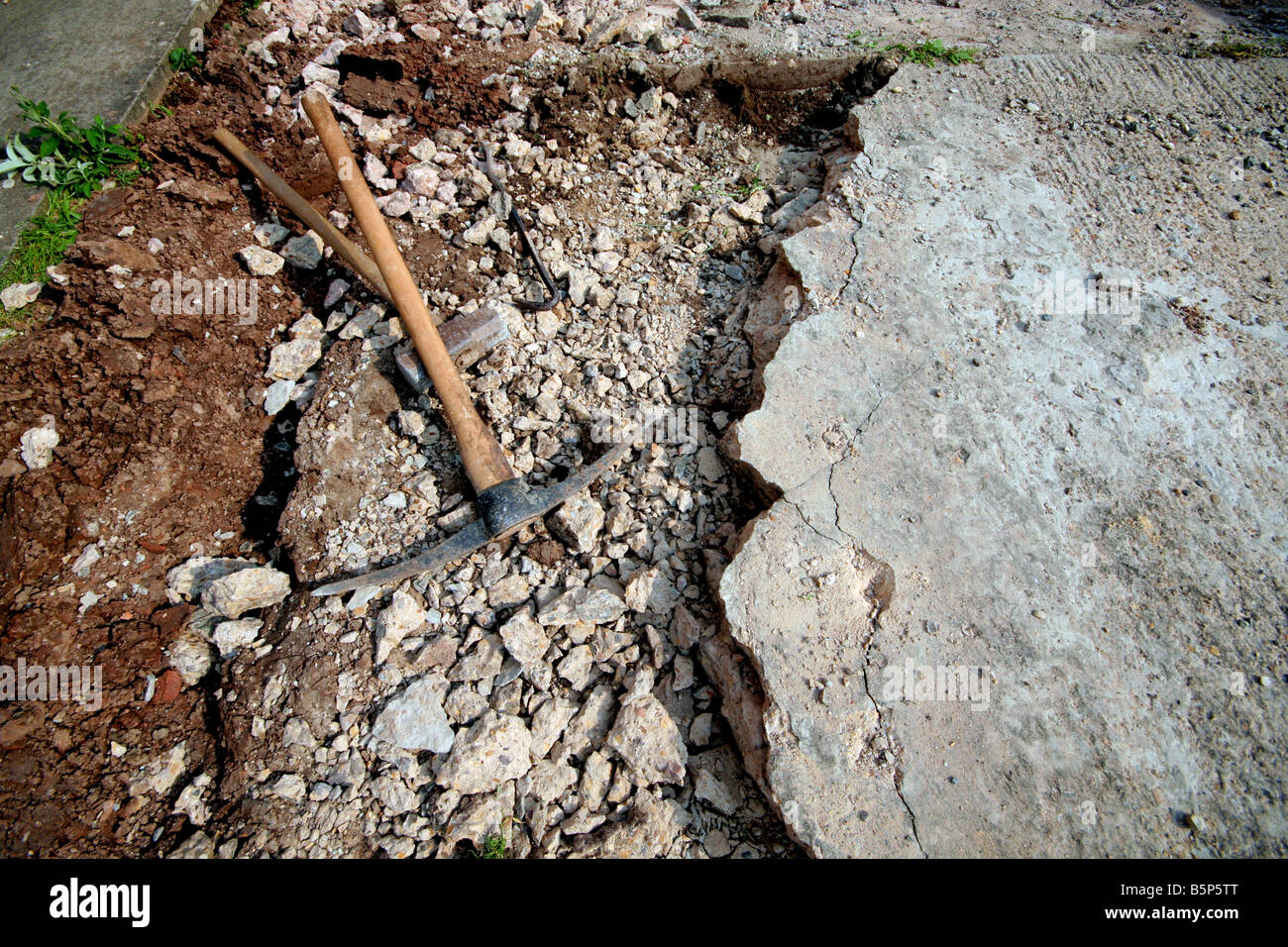 old concrete driveway being broken up with pick axe and sledge hammer Stock Photo