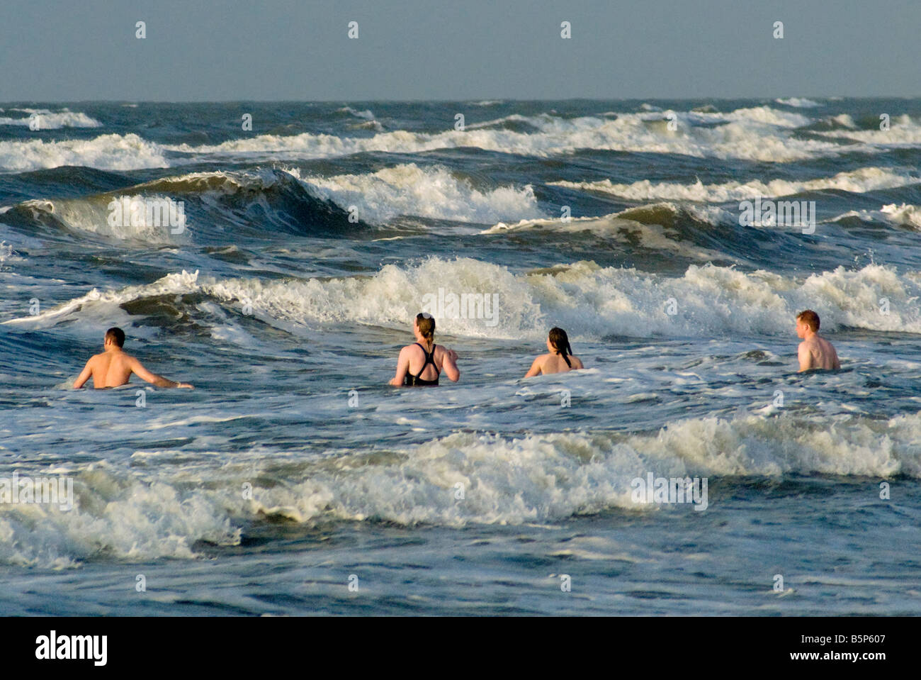 People swimming at Seawall Boulevard beach at sunrise in Galveston