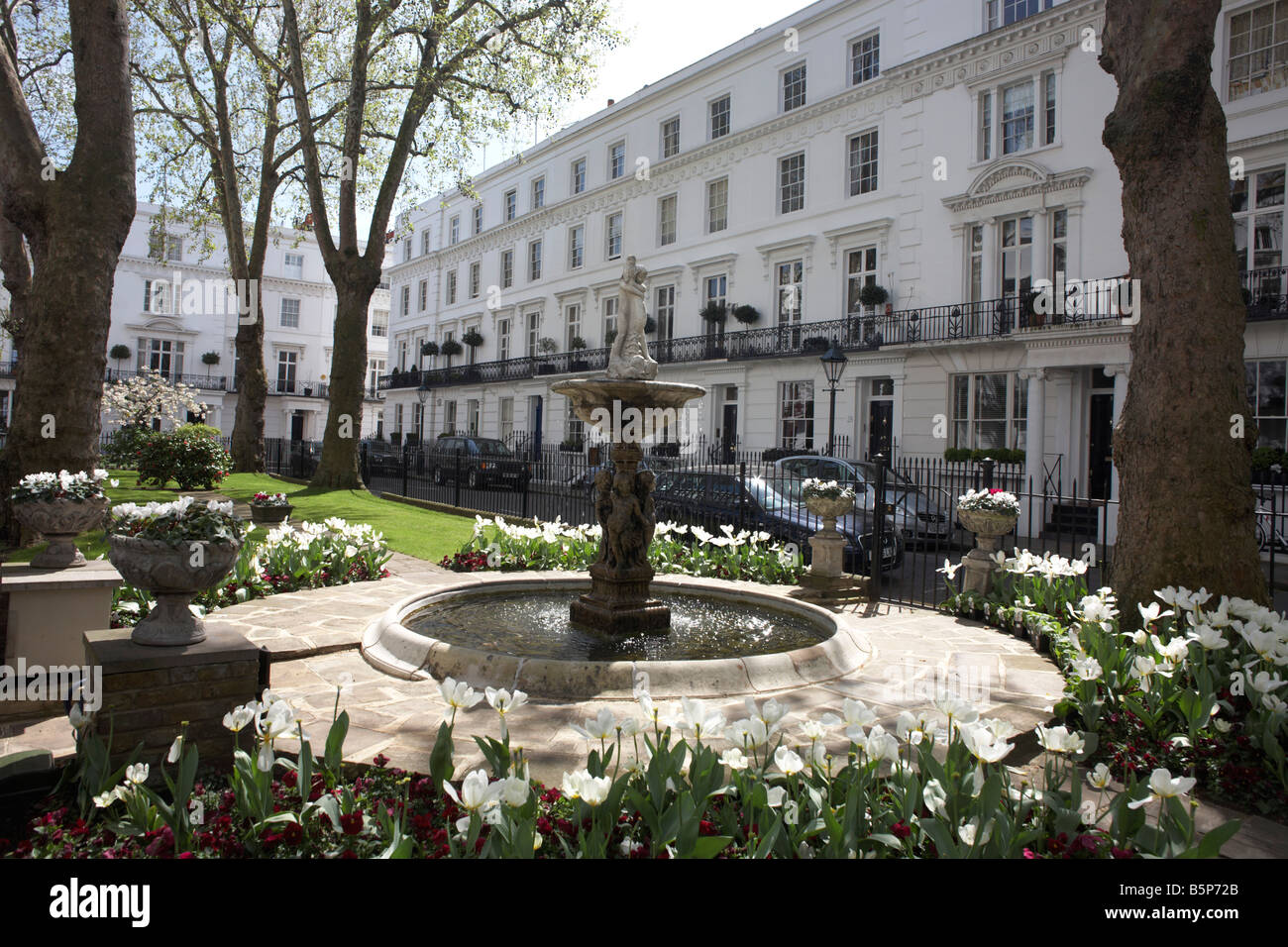 Identical white-painted properties and ornamental fountain with central garden area in exclusive Wellington Square London SW3 Stock Photo