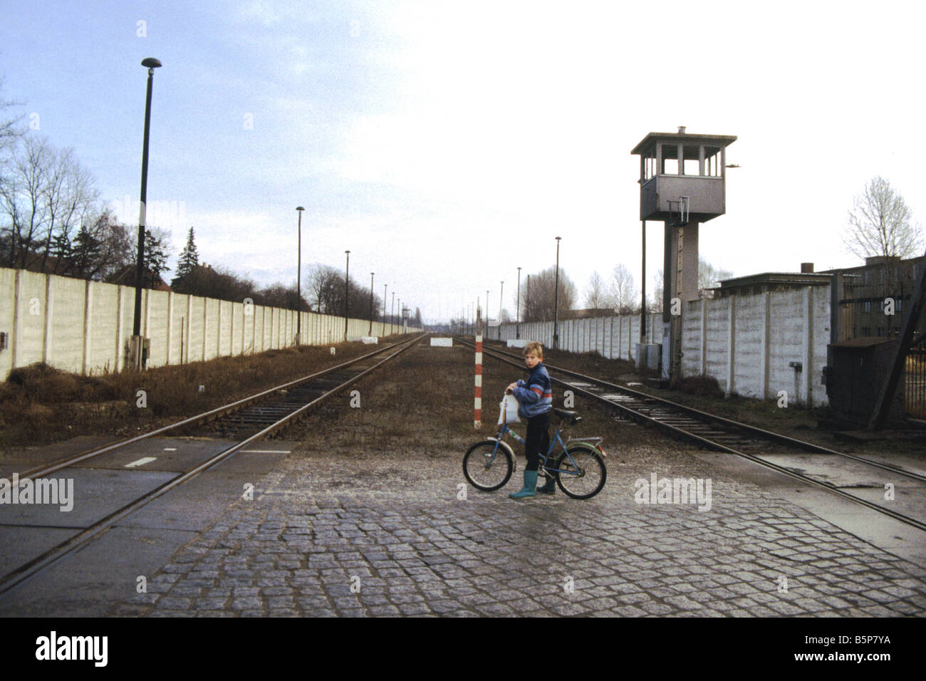 The Berlin Wall at Staaken at the end of the cold War 1991.  A young boy on a bicycle between the railway lines. Stock Photo