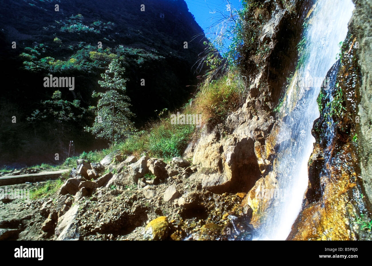 Waterfall and rocks with forest in the background Stock Photo - Alamy