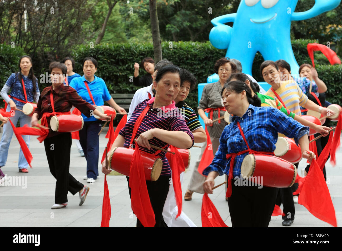 Traditional waist drum dance a part of fitness class for women in Shanghai China with blue World Expo logo in background Stock Photo