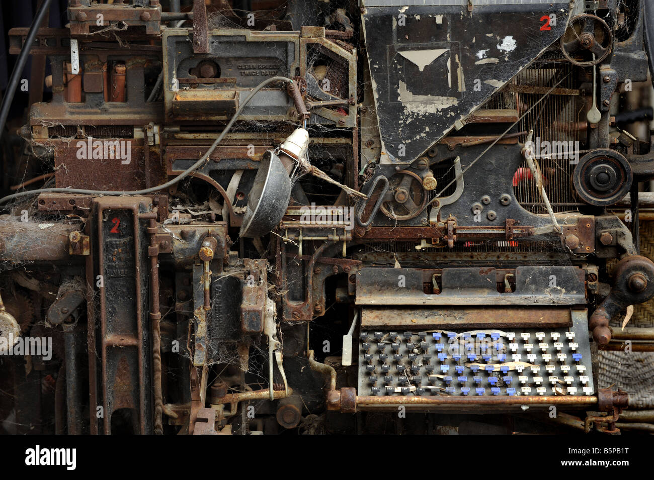 An old Linotype machine used in printing sits rusting in a vacant lot. Stock Photo