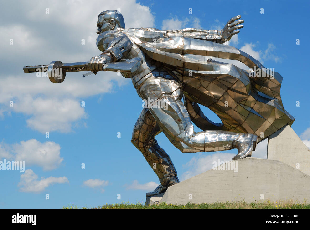 Soldier going in to the attack, metal statue glittered with sun against peaceful azure sky, Ukraine Stock Photo