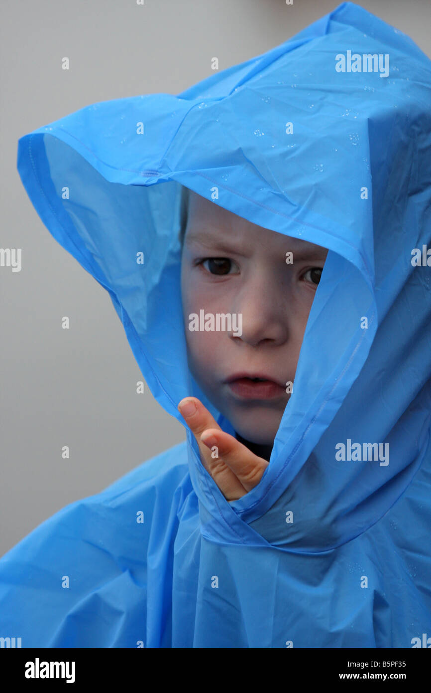 A young child sticking his fingers out of a blue rain poncho or jacket Stock Photo