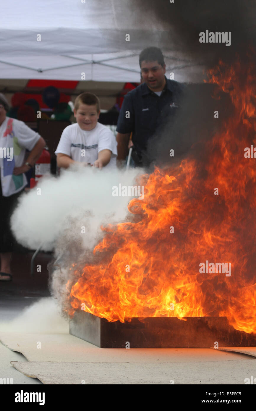 Child using a fire extinguisher to extinguish the flames on a display at a fire fair Stock Photo