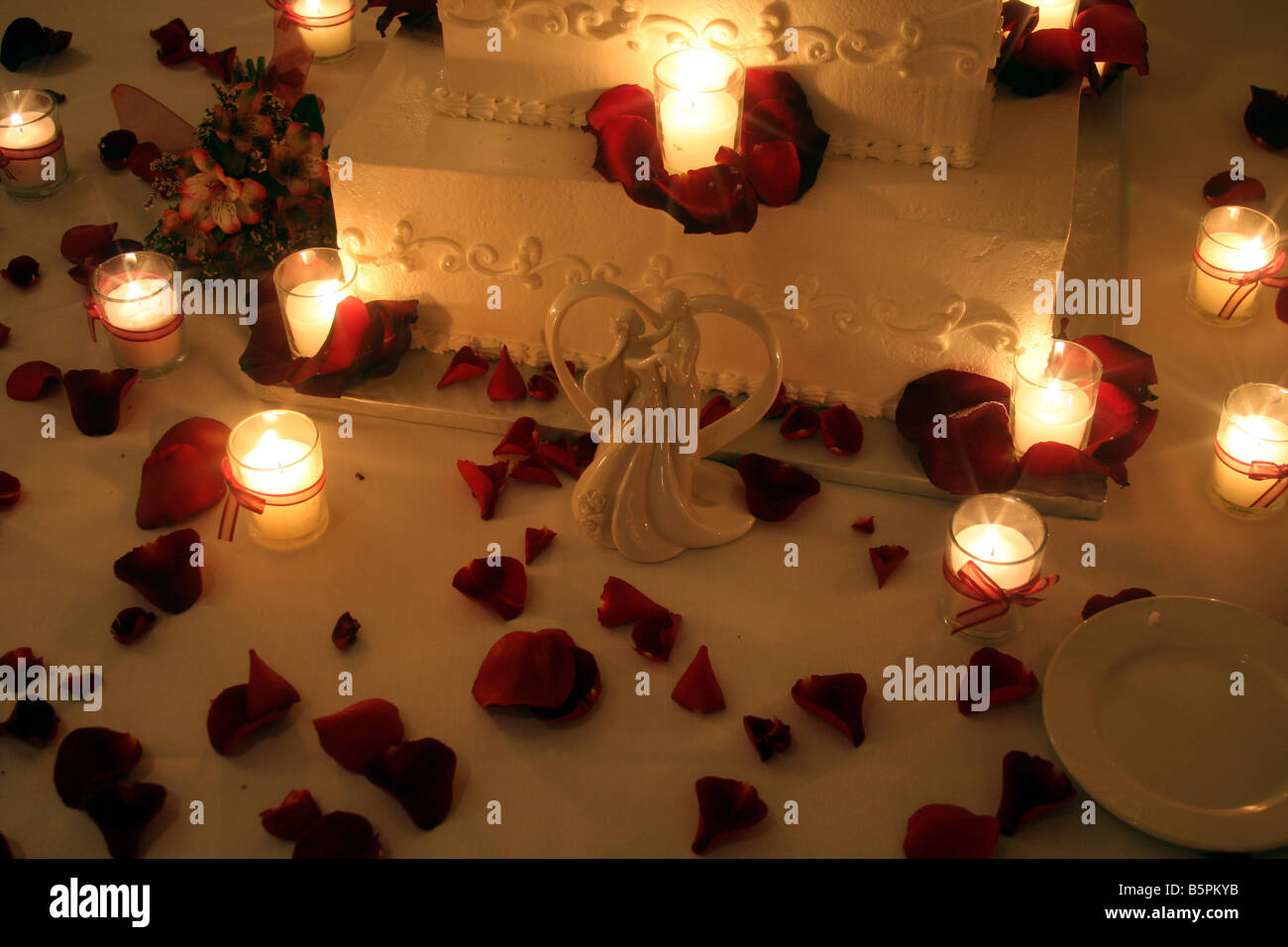 A fancy wedding cake with candles burning around the cake displayed for a wedding reception Stock Photo