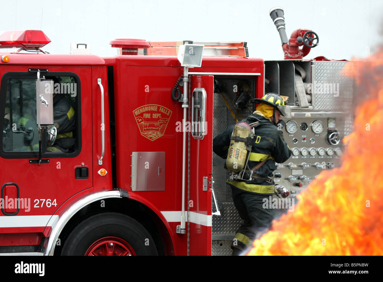 A fire truck arriving at an emergency fire scene and fire fighters are