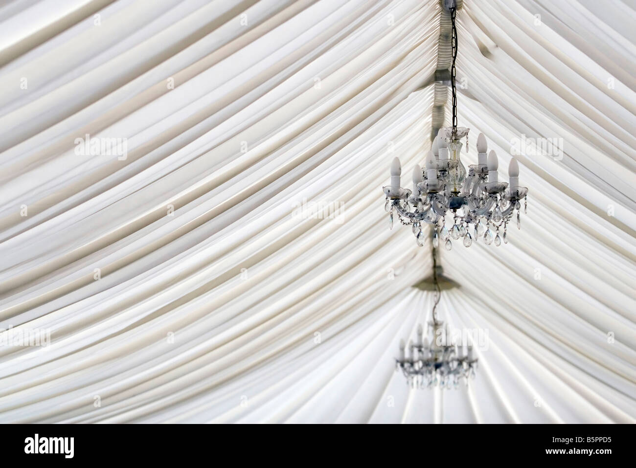 The interior of a wedding marquee with an unlit chandelier highlighting the folds of the fabric. Stock Photo