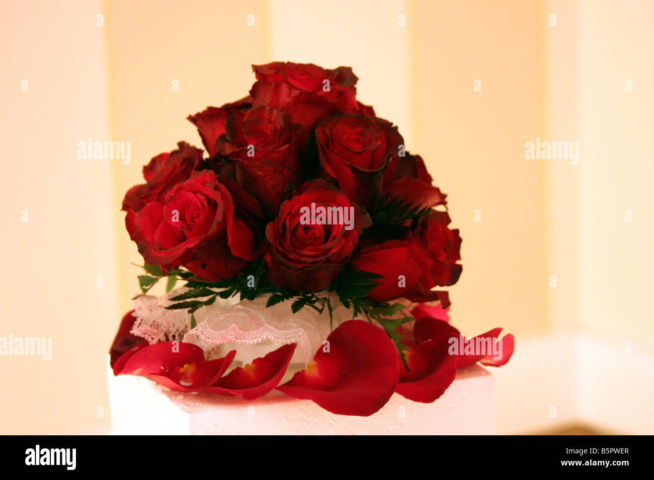 A fancy wedding cake with red roses on top displayed for a wedding reception Stock Photo