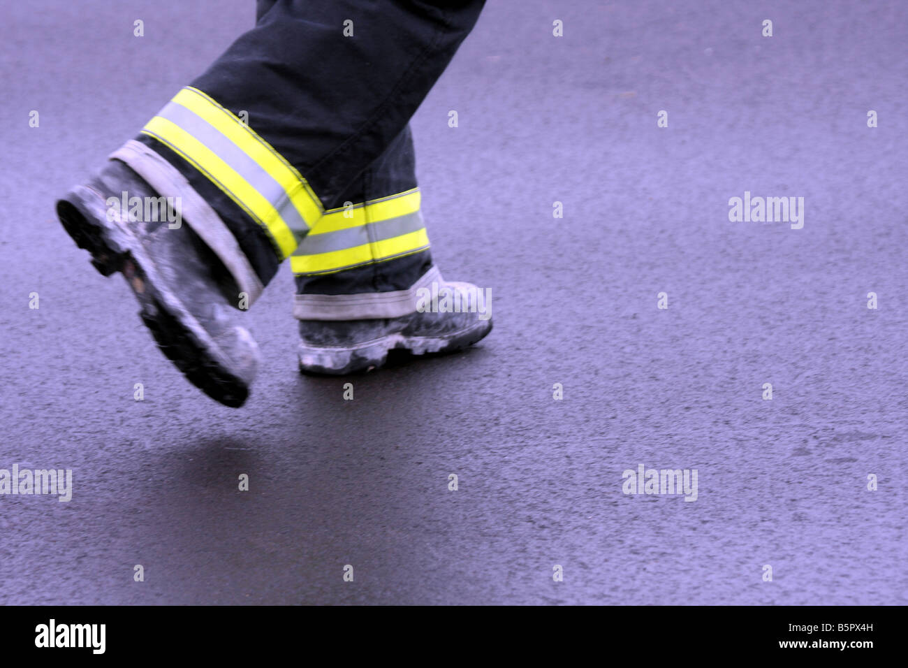 An artistic blur of a fire fighter walking by in bunkers and boots Stock Photo