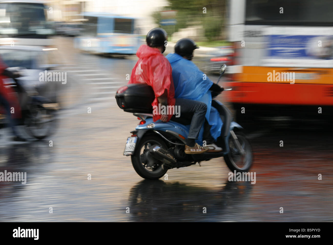 group young tourists riding rental hire scooters mopeds in rain in rome