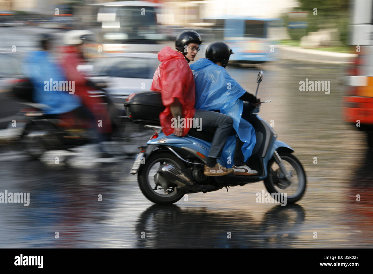 group young tourists riding rental hire scooters mopeds in rain in rome