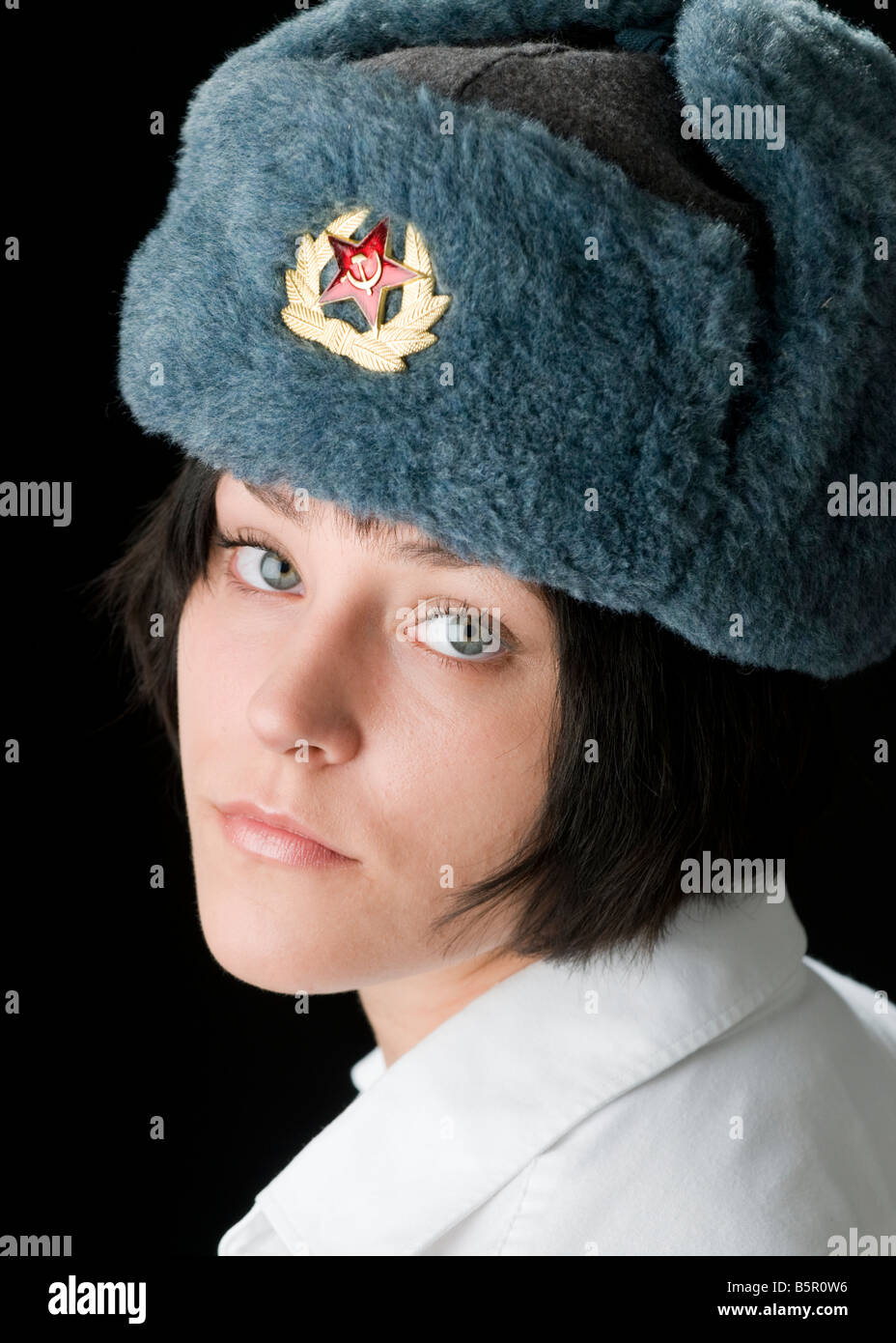 Beautiful blue eyed woman in Russian Ushanka hat with badge of the Soviet Union flag looking over her shoulder Stock Photo