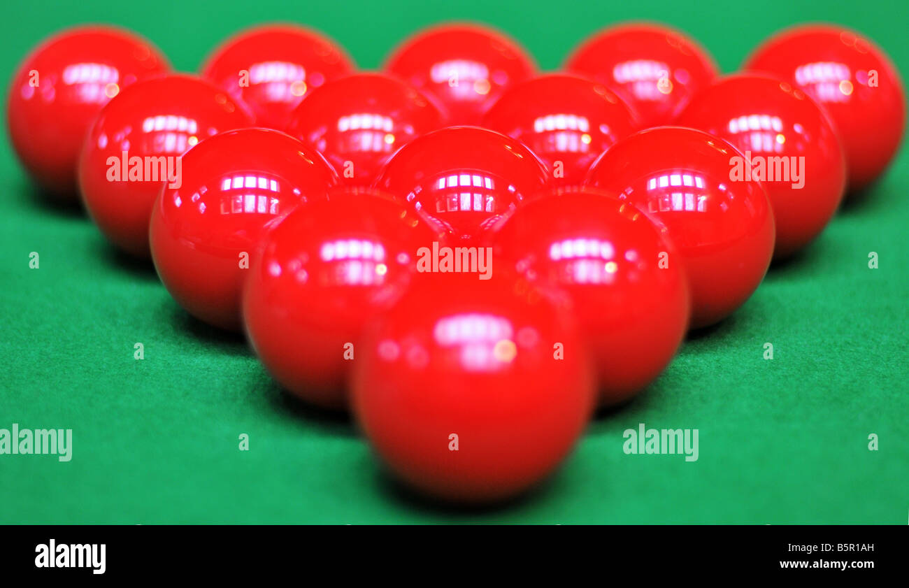 A perfectly racked triangle of snooker, red billiard balls, reflecting the skylight on the green felt of the pool table Stock Photo