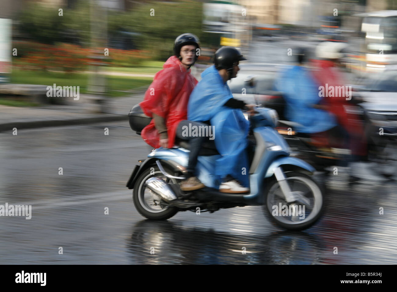 group young tourists riding rental hire scooters mopeds in rain in rome
