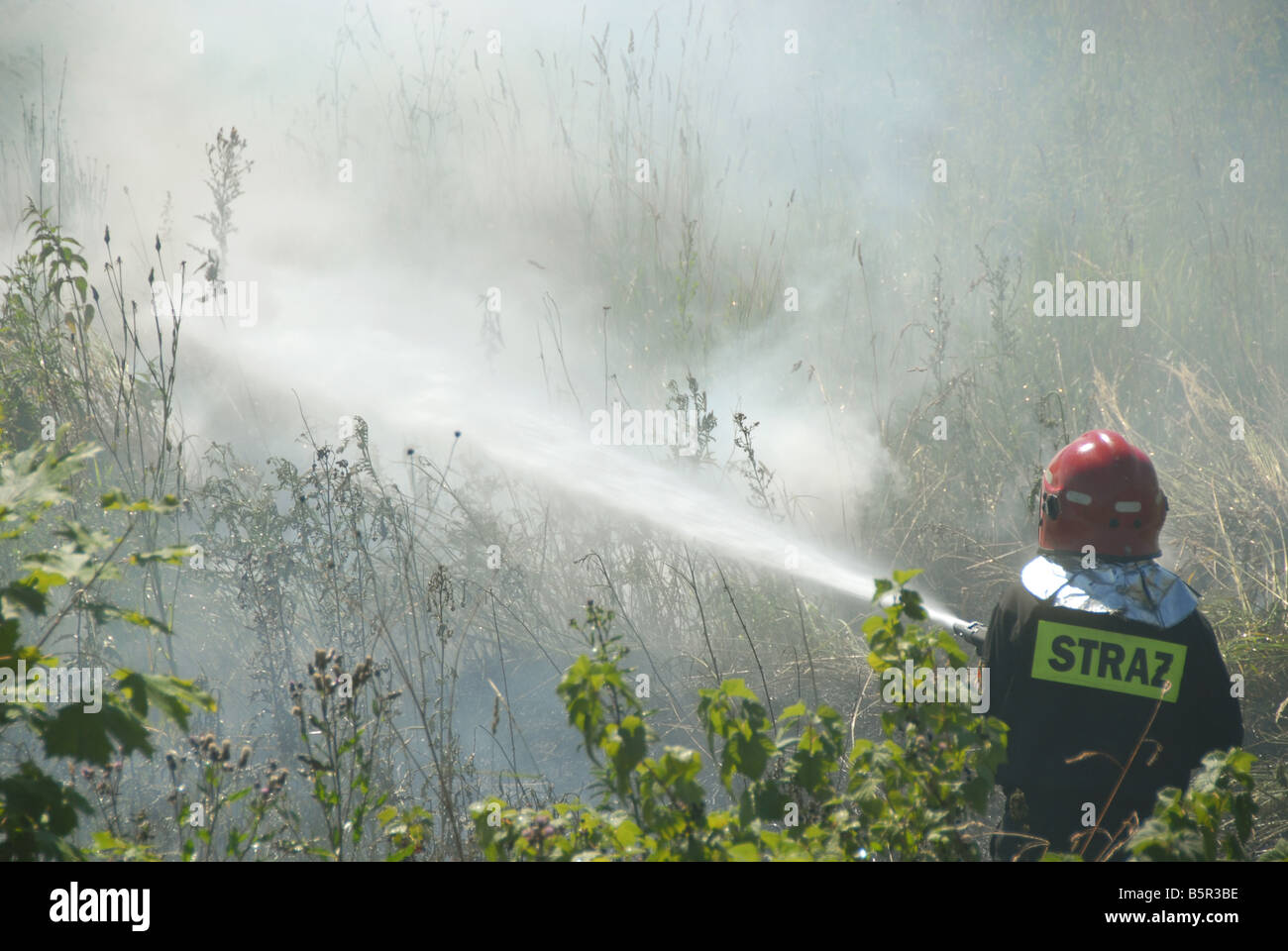 Firefighters using a hose reel jet on a heath fire Stock Photo