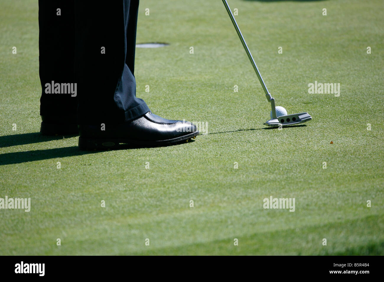 Close-up of a golfer's feet with a putter and ball. Stock Photo