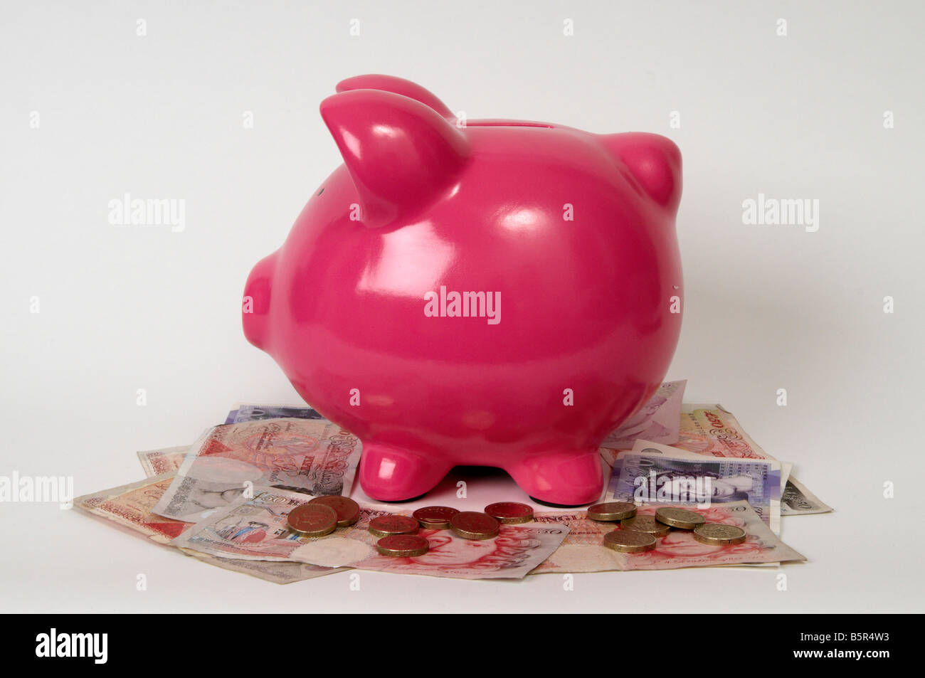 Pink piggy bank sitting on a pile of British Pounds bank notes Stock ...
