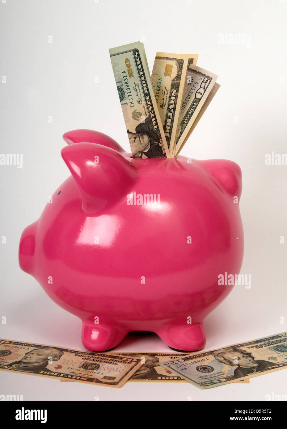 pink piggy bank sitting on a pile bank notes with American Dollars ...