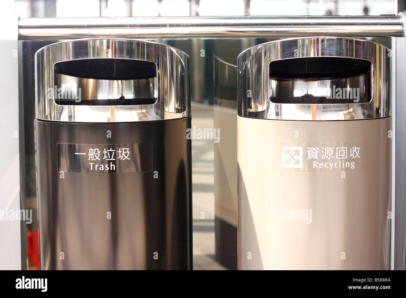 Trash and recycle cans with bilingual signs on them. Stock Photo