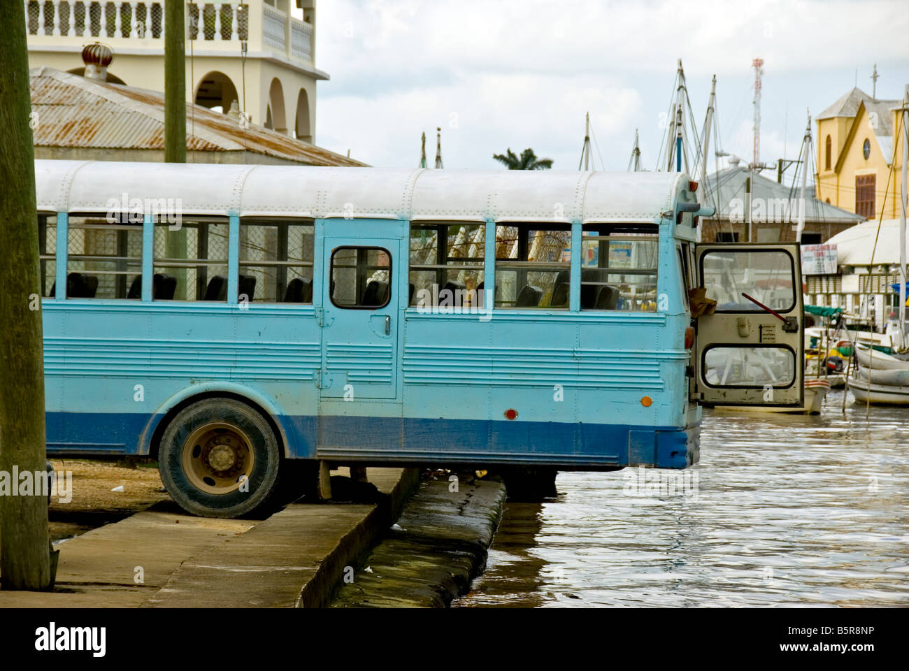 Belize City humor bus backed over river for better air flow in precarious situation Stock Photo