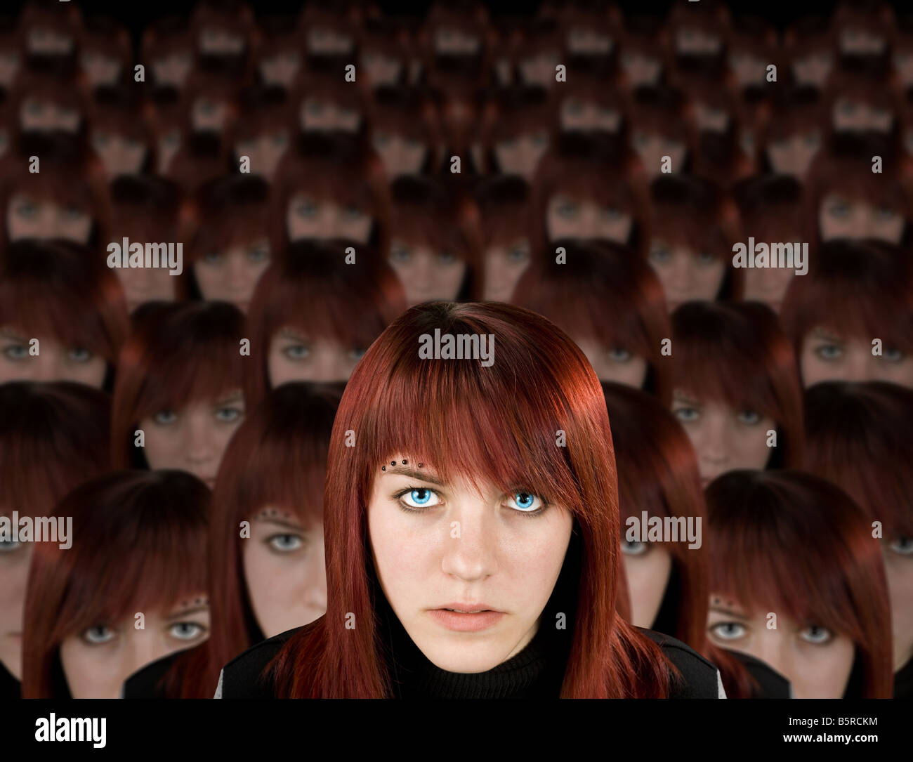 Beautiful redhead girl with piercing and hundred clones staring at camera Stock Photo