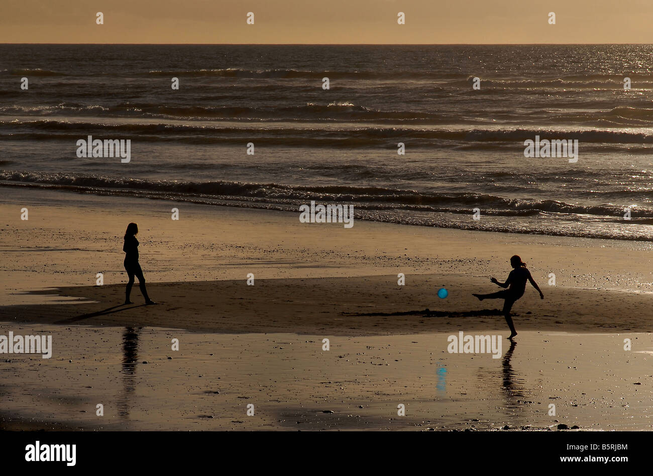 Silhouetted young women playing with a balloon on beach at Greymouth on South Island, New Zealand. Tasman Sea Stock Photo