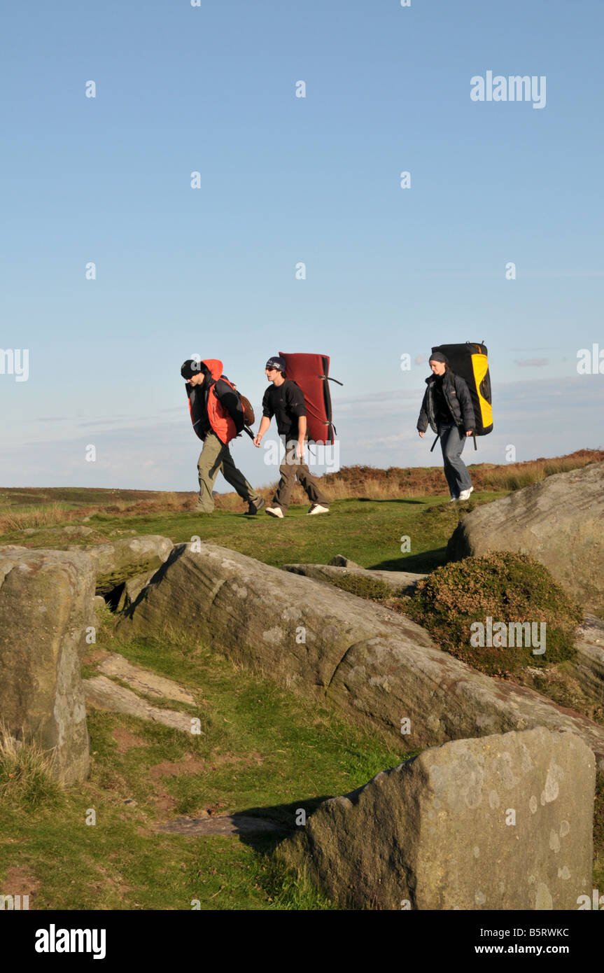 Three young men carrying crash pads walking on Froggatt edge in the Peak District Derbyshire England Stock Photo