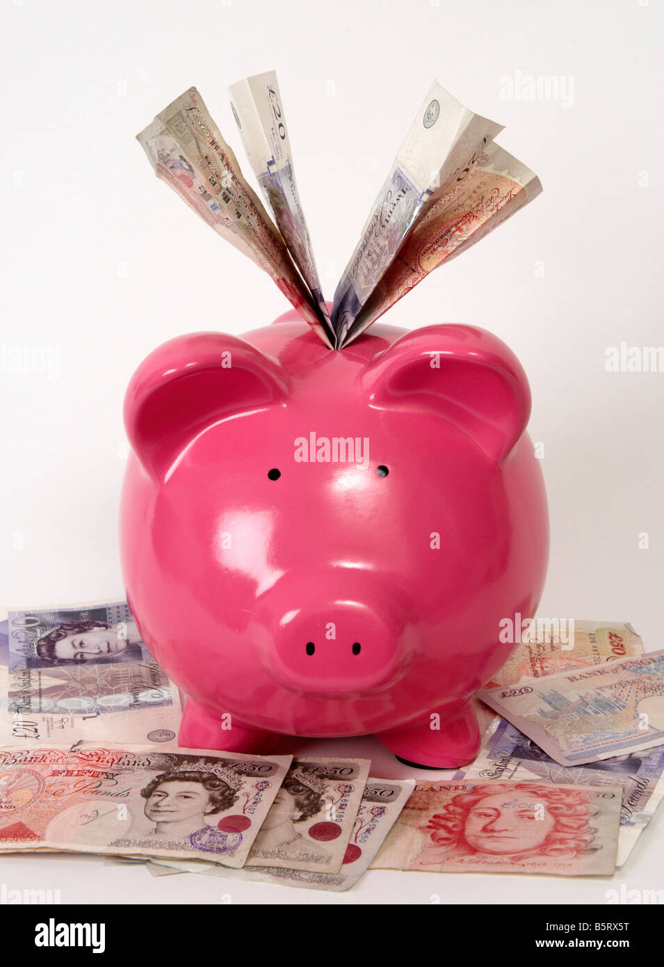 pink piggy bank sitting on a pile of British bank notes with bank notes