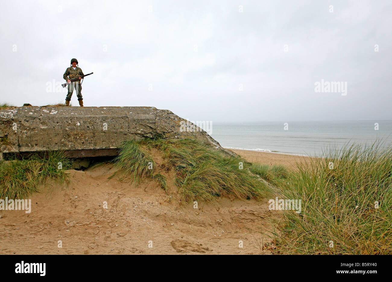 actor dressed as a D-Day  American soldier  standing on a german bunker looking out on  Utah Beach Normandy ,France Stock Photo