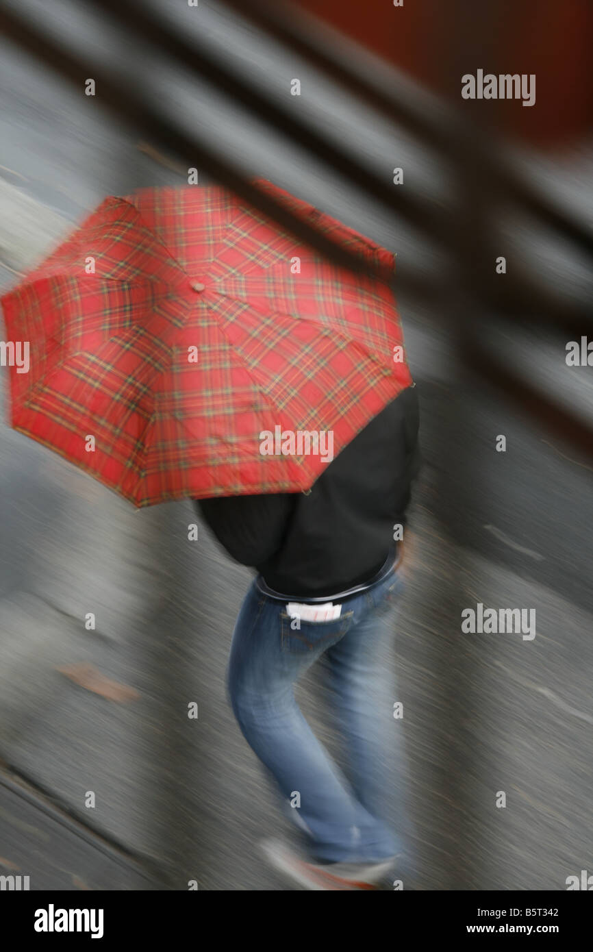 person with red umbrella walking in rain in town Stock Photo - Alamy