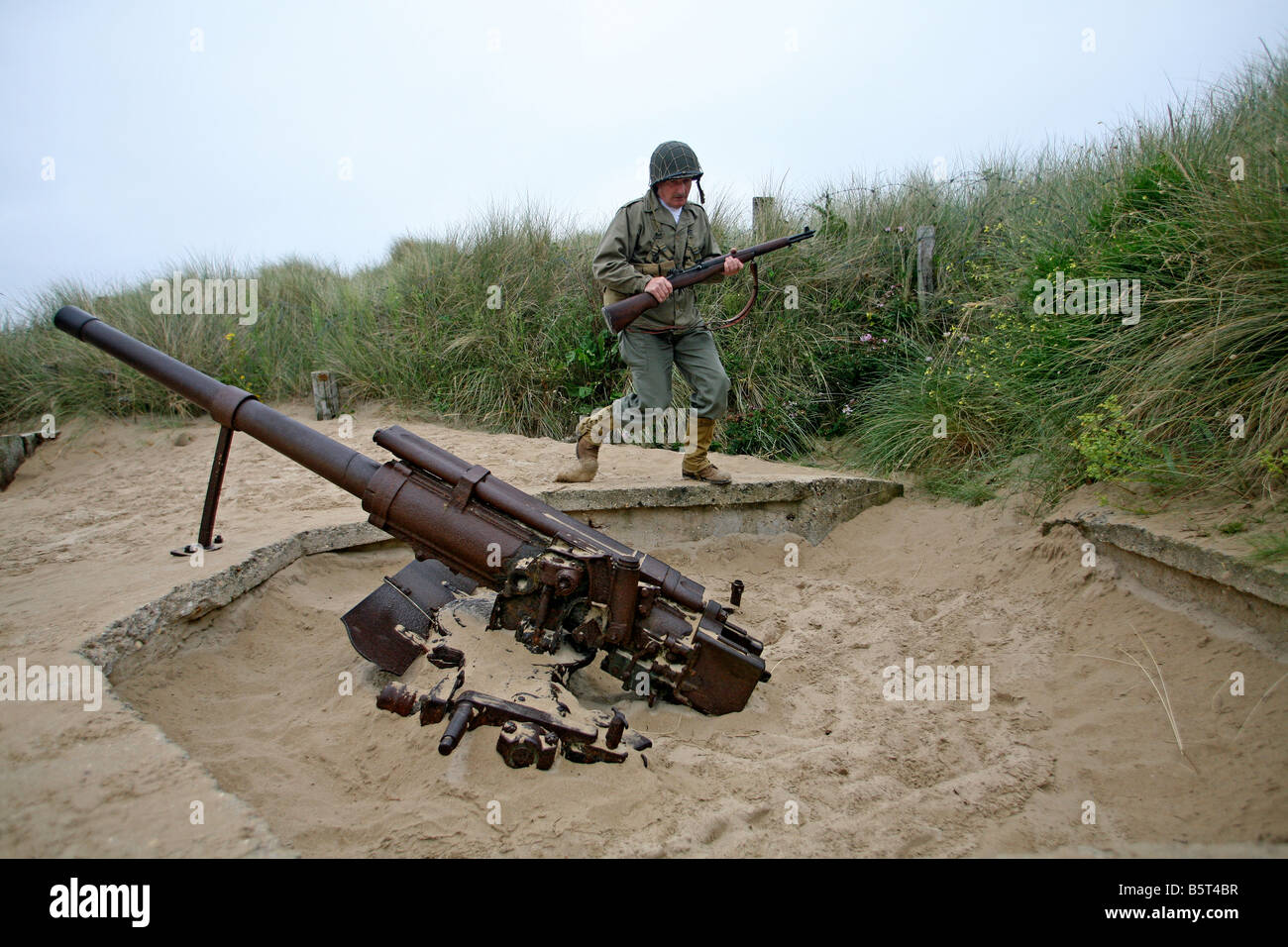 actor dressed as a D-Day  American soldier near a German machinegun  Utah Beach Normandy ,France Stock Photo