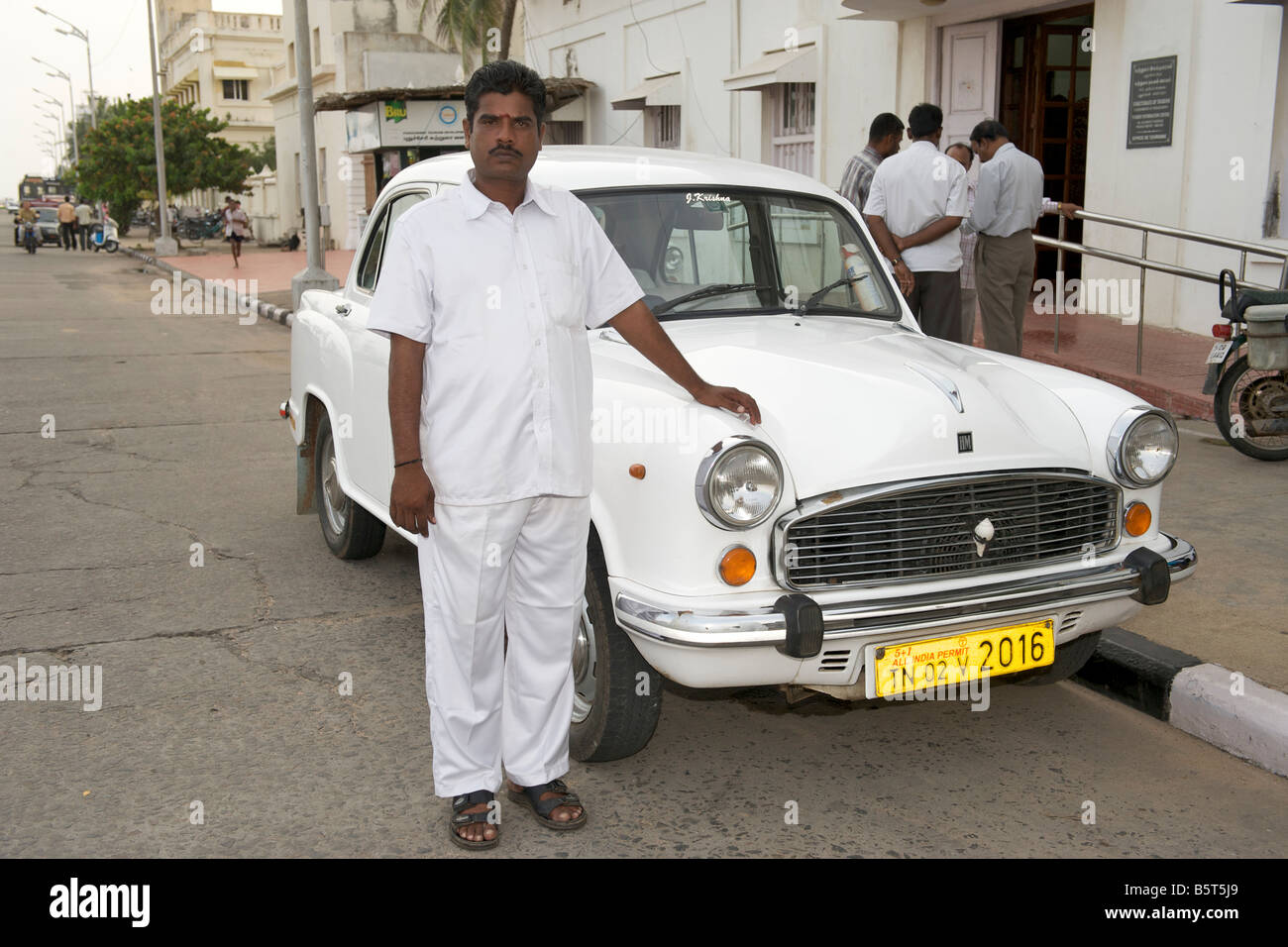 Indian man standing proudly alongside his Ambassador car in Pondicherry India. Stock Photo
