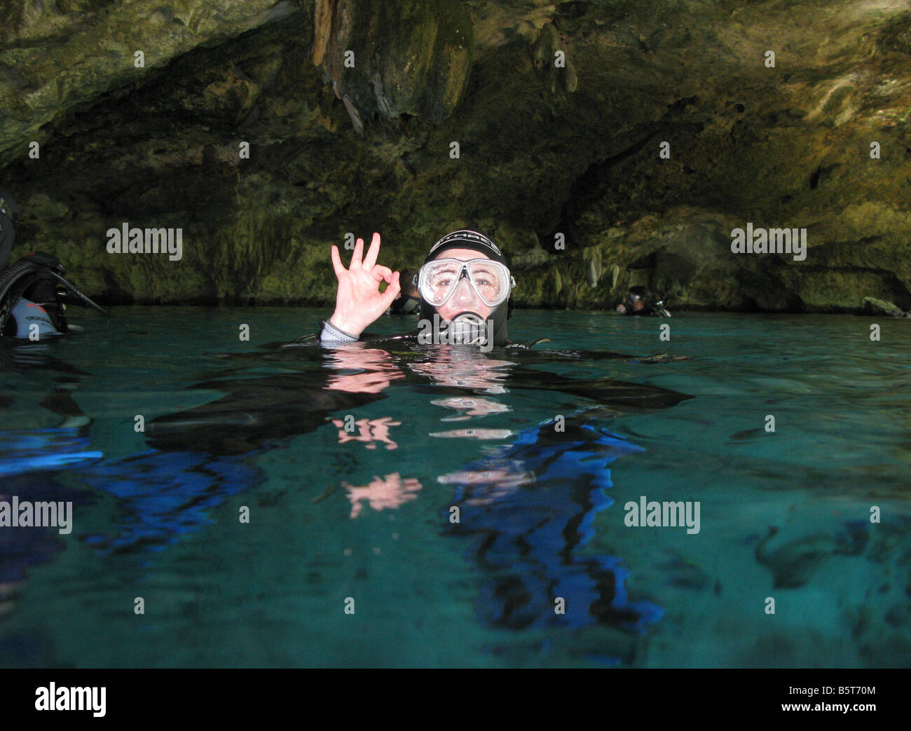 Female diver on surface of cenote giving OK signal Stock Photo