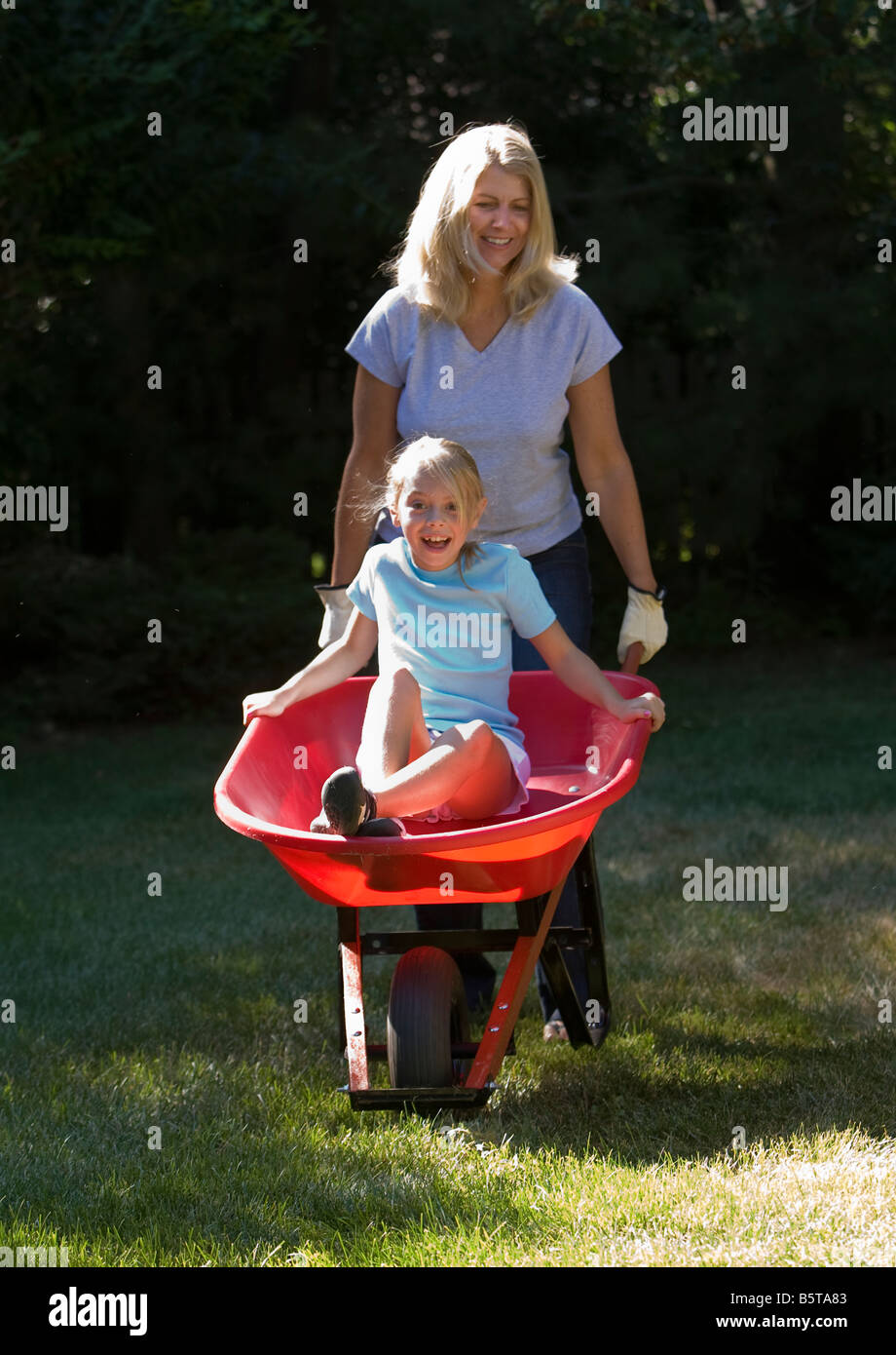 Mother pushing her daughter in a wheelbarrow Stock Photo - Alamy